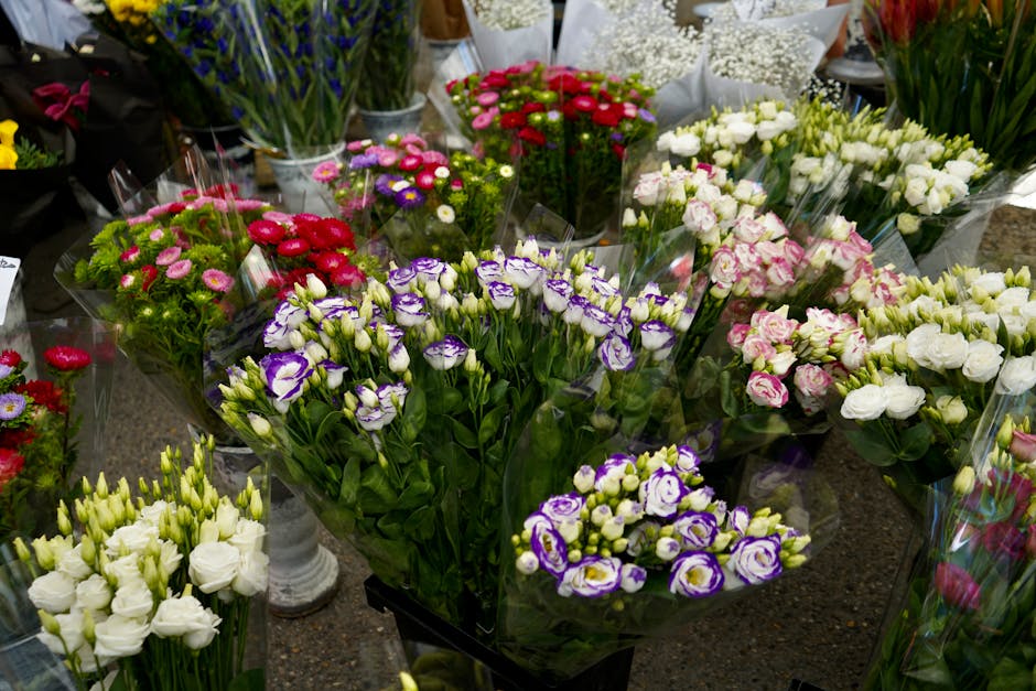A vibrant display of fresh flower bouquets arranged on a dark countertop at Earl's Court Flowers, including purple and white irises with ruffled petals, pink and white miniature roses, and various oth