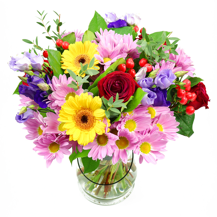 A lavish mixed bouquet rises from a neat glass vase, the overall shape forming a soft, rounded dome of blooms that appears full but not crowded, like a carefully curated display in an Earl's Court shopfront. At the core of the design, velvety red roses draw attention, their petals coiling inward in dense spirals that give the arrangement a touch of classic romance and depth. Flanking them are two bright yellow gerbera daisies with warm brown-orange centres, their layered, radiating petals evoking miniature suns that infuse the bouquet with light-hearted energy. Encircling these standout flowers, generous sprays of pink and light lavender daisies or chrysanthemums add volume and a sense of easy charm, each small blossom with its cluster of narrow petals and yellow centre forming a soft, textural backdrop. Threading their way through this cushion of blooms, stems of lisianthus in shades of purple and lilac introduce graceful, bell-shaped flowers with gently ruffled edges, lending a cool, sophisticated accent that feels in tune with the elegant streets and crescents around Earl's Court. Scattered among the petals, tight clusters of glossy red hypericum berries offer a tactile contrast-small, rounded, and smooth-creating moments of visual surprise. A blend of green foliage, from broad, polished leaves to slender, slightly arching sprigs, fans out to frame the bouquet, enhancing the colours while hinting at natural movement, as if caught in a soft breeze along Warwick Road. The crystal-clear vase reveals the cleanly cut stems immersed in fresh water, underscoring both the freshness of the flowers and the thoughtful craftsmanship behind the arrangement. Overall, the bouquet radiates warmth and celebration, ideal as a gift for birthdays, dinner parties, or thoughtful gestures, delivered to homes and offices throughout Earl's Court and its neighbouring streets.