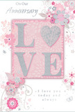 This anniversary card, shown in a well-lit, close composition, feels like a delicate love note shaped by the same care that goes into arranging a romantic bouquet in Earls Court. The focal point is the word LOVE, spelled out in soft, raised lettering that looks inviting to touch, each letter edged and dusted with fine, shimmering glitter. The sparkle is subtle, catching hints of silver and blush as it reflects the light, much like candlelight glancing off pale petals on an intimate anniversary table. This central word is framed by a blush-pink panel that glows gently against a surrounding field of pearly white and gentle grey tones, creating a balanced, calming canvas. Around the centre, softly illustrated flowers open in hues of blush pink, mauve, and creamy white, their petals outlined in delicate grey and brushed with the faintest shadows. These blooms drift along slender stems and curling vines, evoking the airy charm of an English spring garden, the kind you might imagine tucked behind the elegant terraces of Earls Court and nearby Chelsea. Tiny decorative flourishes-floating petals, small butterflies, and swirling tendrils-add movement and a sense of lighthearted romance. Subtle silver accents glint along some edges, giving the design depth and a celebratory sparkle without losing its gentle feel. The words On Our Anniversary and I love you today and always are set in a refined script, their looping letters echoing the curves of the illustrated foliage. Altogether, the card reads as a soft, heartfelt tribute to shared years and quiet moments, perfectly suited to accompany a fresh anniversary bouquet delivered across Earls Court, Gloucester Road, and the neighbouring streets.